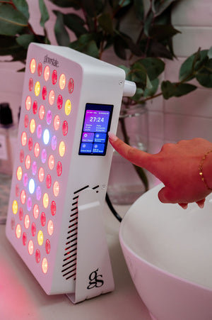 The Radiance60 red light panel touchscreen used by a lady, the panel placed on benchtop, glowing LEDs shine.