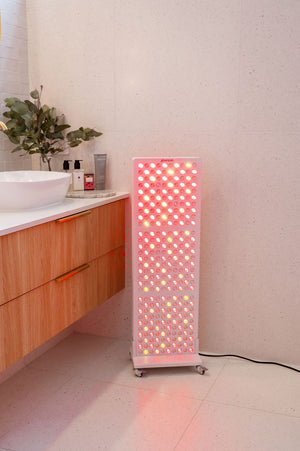 The Radiance300 red light panel in bathroom on a mobile stand, the panel is powered on with LEDs glowing.