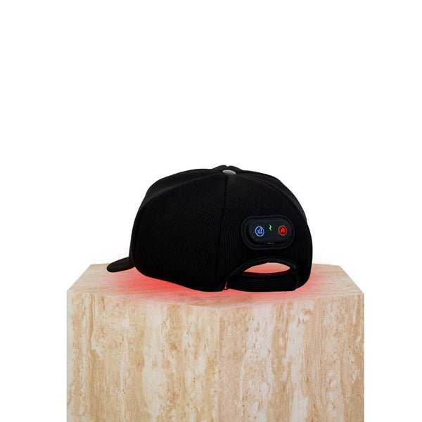 The Halo red light therapy cap sitting on a plinth showing the control panel with glowing LEDs on.