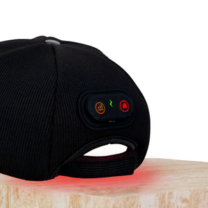 The Halo red light therapy cap sitting on a plinth showing the control panel in breathing mode, full power, LEDs glowing.
