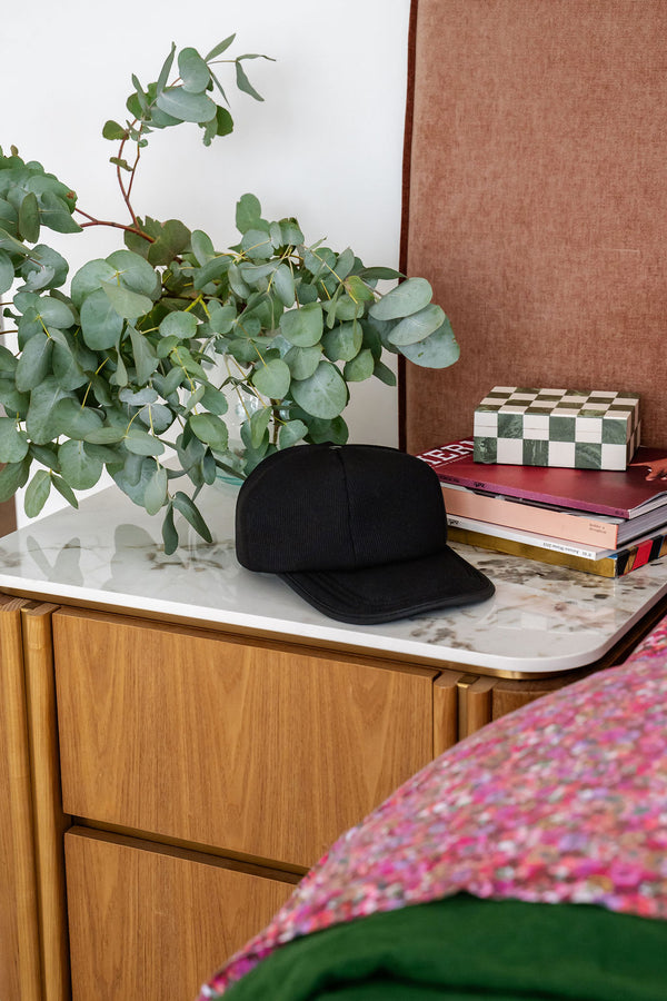 The Halo red light therapy cap is placed on a bedside table in a luxurious bedroom setting.