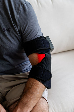 The Focus Flex Joint Wrap, a flexible red light therapy joint wrap is shown attached to a man's elbow with LEDs glowing.